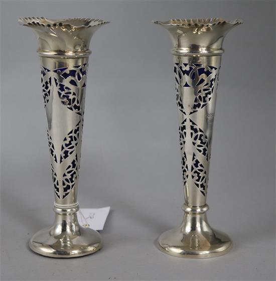 A matched pair of Edwardian pierced silver posy vases with blue glass liners, Birmingham, 1903 & 1906, 95mm.